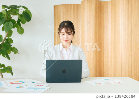 オフィスでノートパソコンを使い資料を確認する若い女性ビジネスパーソン・白スーツ姿の会社員 オフィスでノートパソコンを使い資料を確認する若い女性ビジネスパーソン・白スーツ姿の会社員 139420584