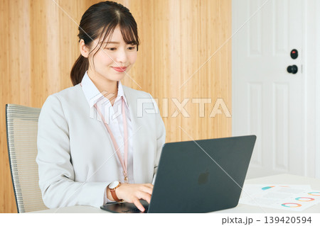 オフィスでノートパソコンを操作する若い女性ビジネスパーソン・白いジャケット姿の会社員がデスクワークに 139420594