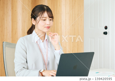 オフィスでノートパソコンを見ながら考える若い女性ビジネスパーソン・スーツ姿の会社員 139420595