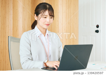 オフィスでノートパソコンを操作する若い女性ビジネスパーソン・スーツ姿で業務に集中する会社員 オフィスでノートパソコンを操作する若い女性ビジネスパーソン・スーツ姿で業務に集中する会社員 139420597