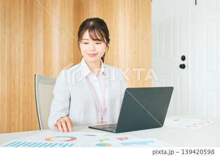 オフィスでノートパソコンと資料を使って仕事をする若い日本人女性ビジネスパーソン・スーツ姿の会社員 139420598