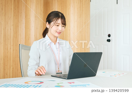 オフィスでノートパソコンを使いながら資料を確認する若い女性ビジネスパーソン・スーツ姿の会社員 139420599