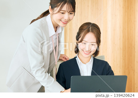 オフィスでノートパソコンを見ながら先輩社員から指導を受ける新入社員の女性ビジネスウーマン オフィスでノートパソコンを見ながら先輩社員から指導を受ける新入社員の女性ビジネスウーマン 139420624