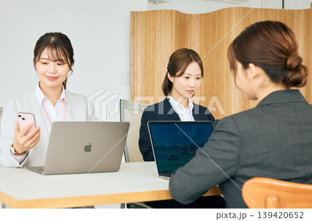 オフィスの会議テーブルでノートパソコンとスマートフォンを使いながら打ち合わせをする3人の女性ビジネス オフィスの会議テーブルでノートパソコンとスマートフォンを使いながら打ち合わせをする3人の女性ビジネス 139420652