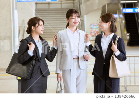 駅構内で会話する3人の女性ビジネスパーソン・スーツ姿で笑顔の通勤風景 駅構内で会話する3人の女性ビジネスパーソン・スーツ姿で笑顔の通勤風景 139420666