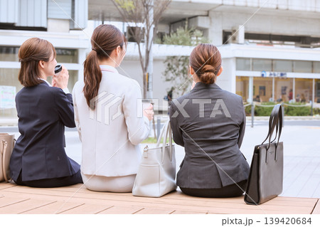 都市のベンチに座って休憩する3人のビジネスウーマン・スーツ姿の女性会社員の後ろ姿 都市のベンチに座って休憩する3人のビジネスウーマン・スーツ姿の女性会社員の後ろ姿 139420684