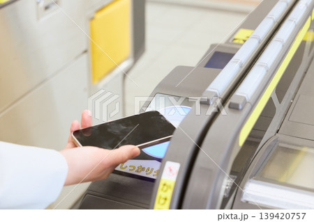 駅の自動改札機にスマートフォンをかざして通過する人・モバイルSuicaで電車に乗る日常シーン 駅の自動改札機にスマートフォンをかざして通過する人・モバイルSuicaで電車に乗る日常シーン 139420757