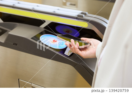 駅の自動改札機にスマートフォンをかざして通過する人・モバイル交通系ICカード決済イメージ 139420759
