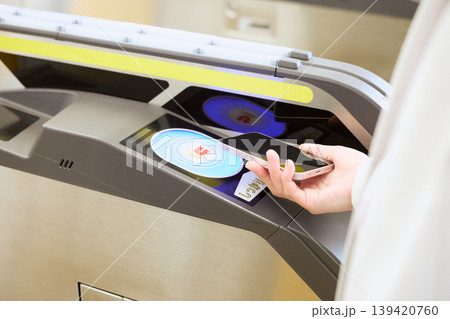 駅の自動改札機にスマートフォンをタッチして通過するモバイル決済・交通系ICカードのイメージ 駅の自動改札機にスマートフォンをタッチして通過するモバイル決済・交通系ICカードのイメージ 139420760