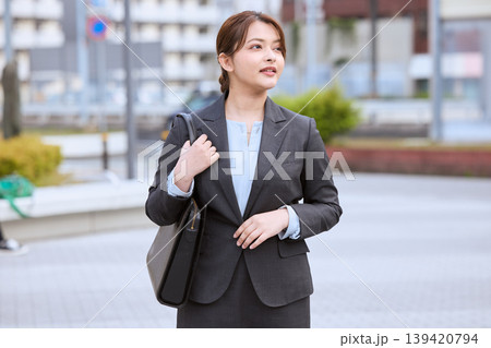 ビジネスバッグを持って外出先を歩く若い女性ビジネスパーソン・スーツ姿で営業に向かう会社員 139420794