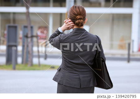 オフィス街で電話をかけながら歩くスーツ姿の女性ビジネスパーソン・後ろ姿 139420795