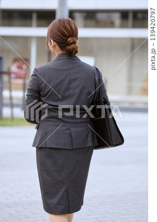 オフィスビルの前を歩くスーツ姿の女性ビジネスパーソン・通勤する会社員の後ろ姿 139420797