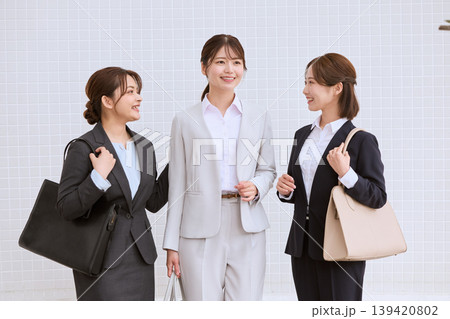 オフィス街で笑顔で会話する3人の若い女性ビジネスパーソン・スーツ姿の新入社員・就職活動中の女子大学生 139420802