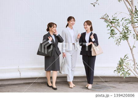 オフィス街で談笑する3人のスーツ姿の若い女性ビジネスパーソン・就職活動・新入社員イメージ オフィス街で談笑する3人のスーツ姿の若い女性ビジネスパーソン・就職活動・新入社員イメージ 139420806