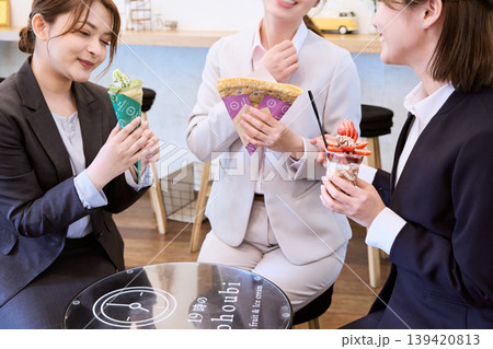 仕事帰りにクレープやパフェを楽しむスーツ姿の女性3人・カフェでのご褒美スイーツタイム 仕事帰りにクレープやパフェを楽しむスーツ姿の女性3人・カフェでのご褒美スイーツタイム 139420813