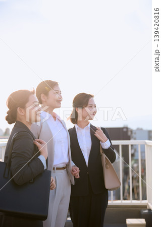 朝日を浴びて前を見つめる3人の女性ビジネスパーソン・スーツ姿で出勤する会社員のビジネスイメージ 朝日を浴びて前を見つめる3人の女性ビジネスパーソン・スーツ姿で出勤する会社員のビジネスイメージ 139420816