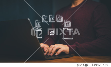 Man using laptop for data transfer, file management, and document management. Digital transformation concept with cloud storage, backup, sharing, and technology workflow. 139421429