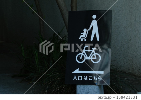 都会の案内サイン：ベビーカーと自転車の入口を示す黒い看板 139421531