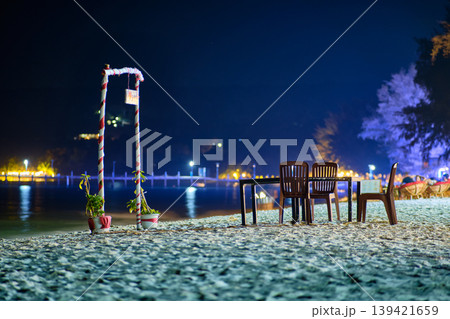 Cozy night seating area on Koh Rong beach with table chairs and red white striped arch Cozy night seating area on Koh Rong beach with table chairs and red white striped arch 139421659