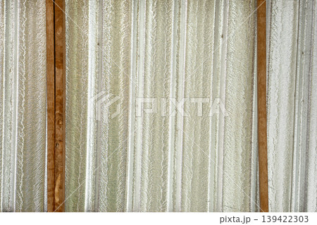 Reflective silver foil insulation installed between wooden beams on a roof ceiling. Textured metallic heat barrier for attic thermal protection and home energy efficiency. Construction site detail. Reflective silver foil insulation installed between wooden beams on a roof ceiling. Textured metallic heat barrier for attic thermal protection and home energy efficiency. Construction site detail. 139422303