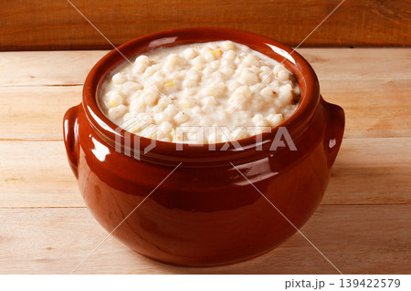 A clay pot filled with creamy white corn porridge, a traditional Brazilian dessert 139422579