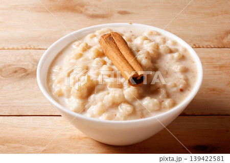 Creamy white corn porridge with cinnamon sticks in a white bowl on a wooden table Creamy white corn porridge with cinnamon sticks in a white bowl on a wooden table 139422581