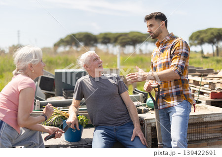 Mature couple and man argue with each other while standing near fence on small farm 139422691