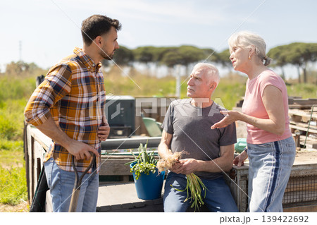 Mature couple and man argue with each other while standing near fence on small farm Mature couple and man argue with each other while standing near fence on small farm 139422692