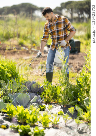 Young man spraying plants on farm field Young man spraying plants on farm field 139422752