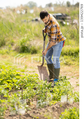Young man with shovel working on farm field Young man with shovel working on farm field 139422769