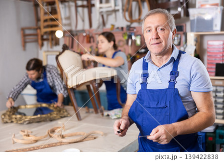 Confident successful craftsman restorer in uniform looking at camera in furniture repair woodwork shop Confident successful craftsman restorer in uniform looking at camera in furniture repair woodwork shop 139422838