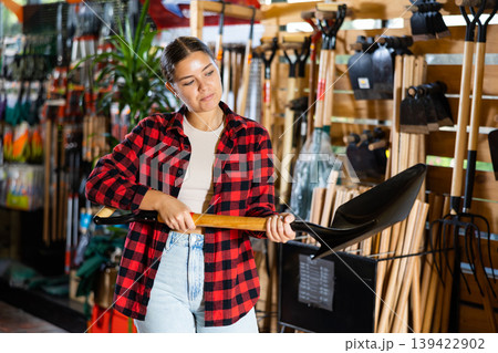 Female farmer choosing shovel in gardening store Female farmer choosing shovel in gardening store 139422902