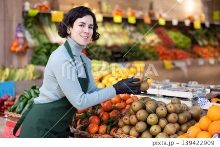 Adult woman seller puts pears on display Adult woman seller puts pears on display 139422909
