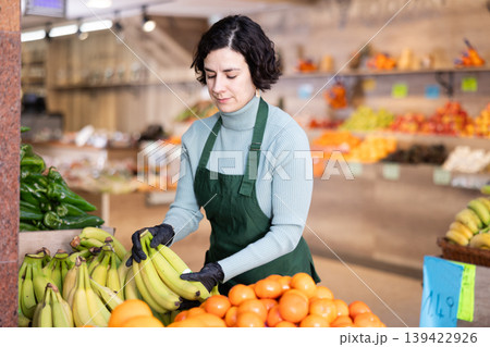 Woman shop seller puts banana goods on display case 139422926