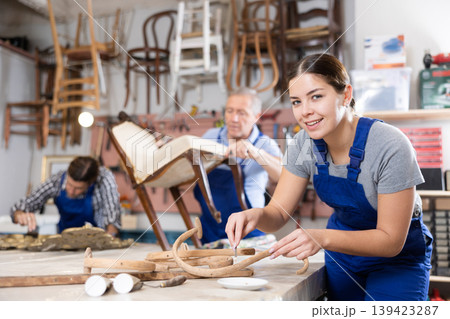 Young female furniture maker working on vintage chair parts in workshop Young female furniture maker working on vintage chair parts in workshop 139423287