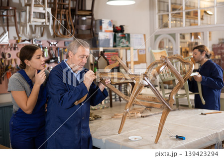 Senior man restorer spackling antique chair surface getting piece of furniture ready for further coloring Senior man restorer spackling antique chair surface getting piece of furniture ready for further coloring 139423294