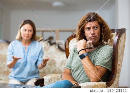 Middle-aged male and female settling relations between themselves sitting on the couch Middle-aged male and female settling relations between themselves sitting on the couch 139423532