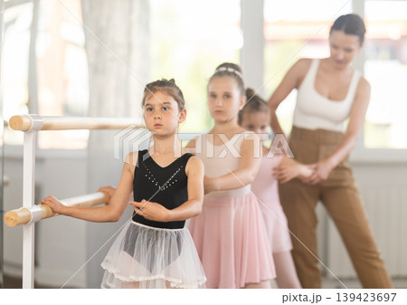Girls in ballet class perform first position with correction of female mentor 139423697