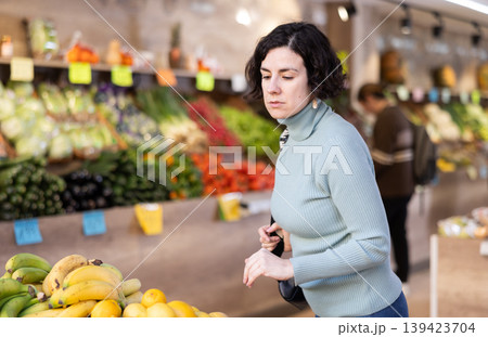 Woman in grocery store choosing fruit Woman in grocery store choosing fruit 139423704