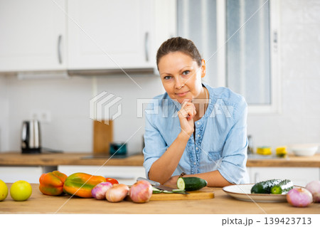 Smiling woman holding face with hand in kitchen at home 139423713
