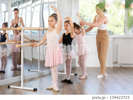 Girls in ballet class perform third position with correction of female mentor 139423725