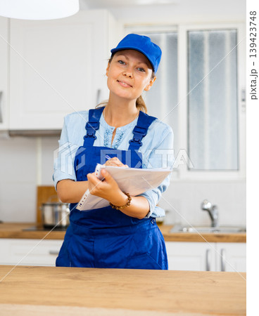 Woman house cleaner making notes in kitchen Woman house cleaner making notes in kitchen 139423748