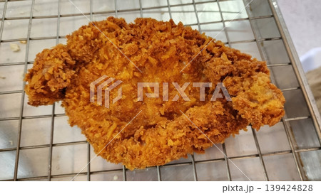 Crispy Golden Brown Tonkatsu Pork Cutlet on Metal Cooling Rack in Restaurant Kitchen 139424828