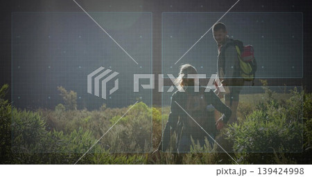 Helping woman climbing sunlit hillside brush by man reaching back, with hiking backpacks and boots 139424998