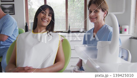 Smiling female patient receiving treatment in green dental chair at dental clinic with dentist Smiling female patient receiving treatment in green dental chair at dental clinic with dentist 139425010