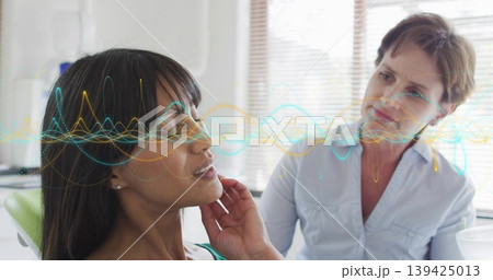 Touching chin patient seated in green chair consulting provider in exam room, with waveform overlay Touching chin patient seated in green chair consulting provider in exam room, with waveform overlay 139425013