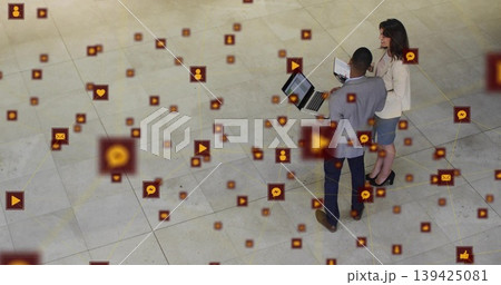 Collaborating suited professionals viewing social media icons on devices in atrium, copy space Collaborating suited professionals viewing social media icons on devices in atrium, copy space 139425081