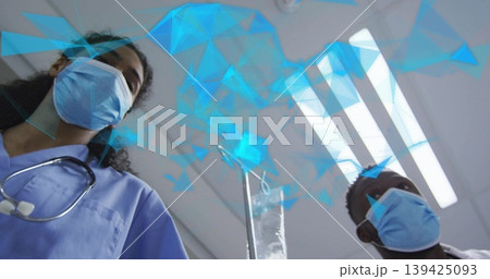 Two medics in scrubs leaning over patient in exam room, with stethoscope IV bag digital overlay Two medics in scrubs leaning over patient in exam room, with stethoscope IV bag digital overlay 139425093