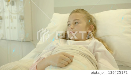 Lying girl wearing gown resting on hospital bed in ward, with blanket pillow monitoring panel Lying girl wearing gown resting on hospital bed in ward, with blanket pillow monitoring panel 139425171