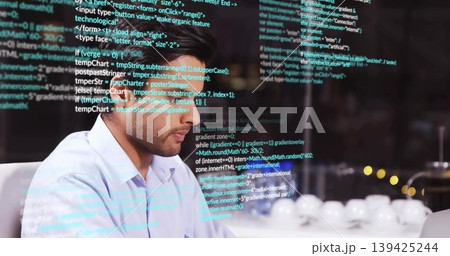 Typing code Asian man wearing blue shirt at office desk, with glass code reflections and cups Typing code Asian man wearing blue shirt at office desk, with glass code reflections and cups 139425244